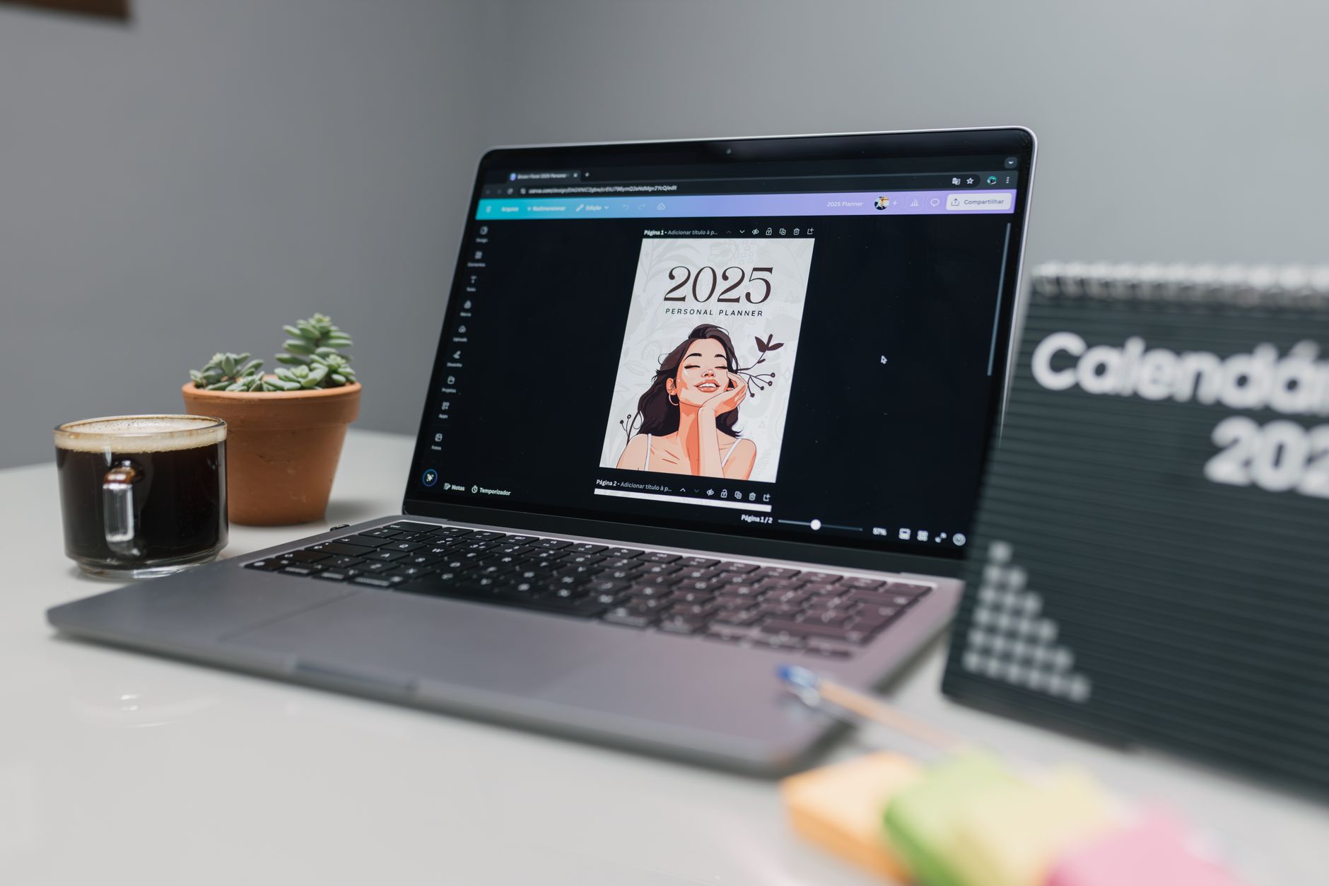 Person working on a laptop while designing a digital planner with coffee nearby